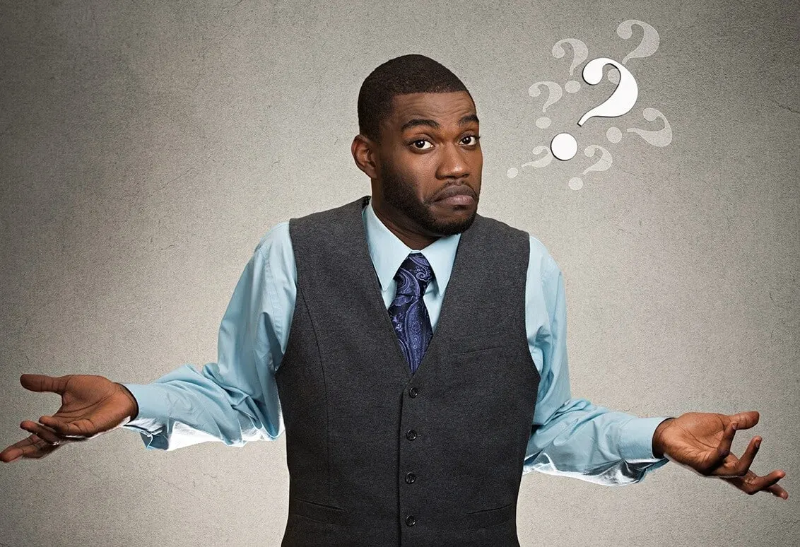 Confused man in a vest shrugging beside question marks